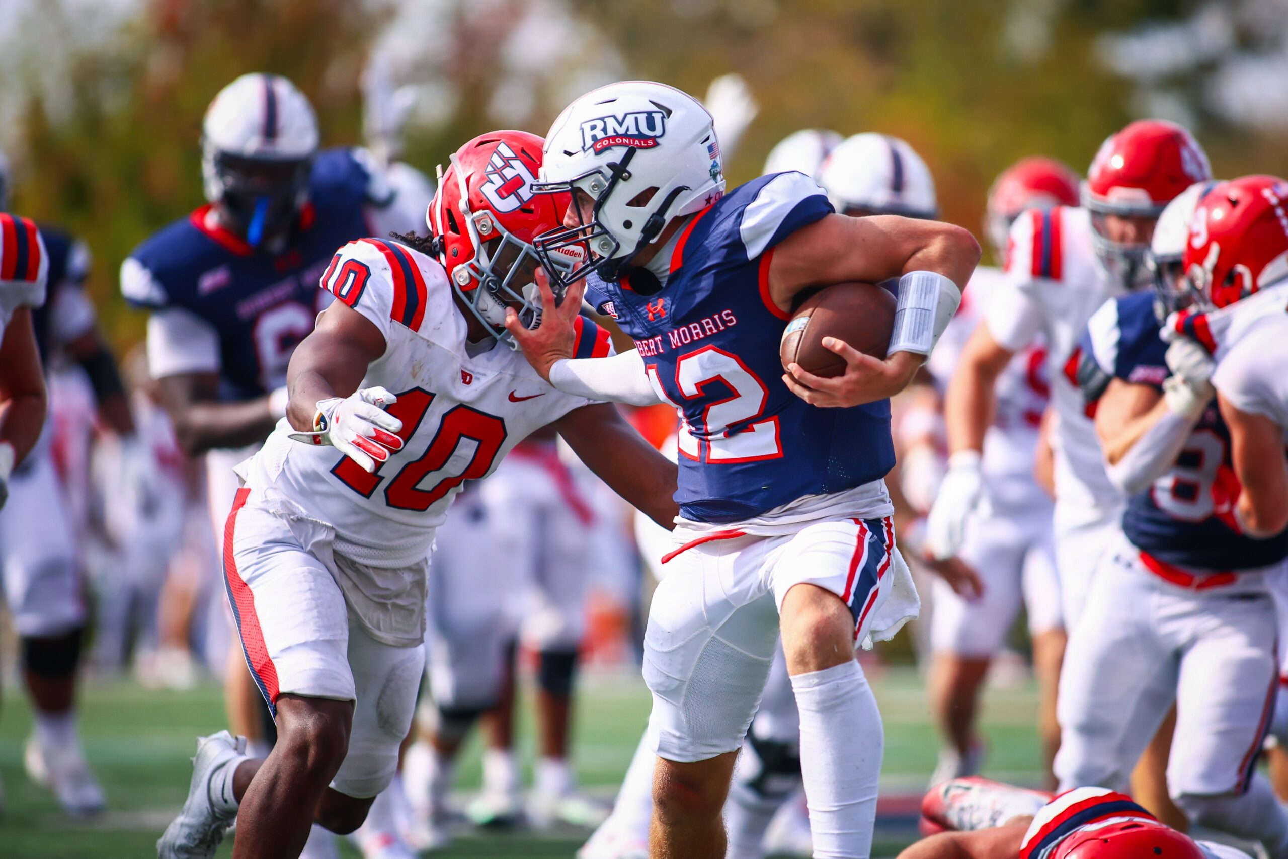 Robert Morris quarterback Jake Wolfe stiff arms a Dayton defender on Sept. 20, 2025 -- RMU Athletics